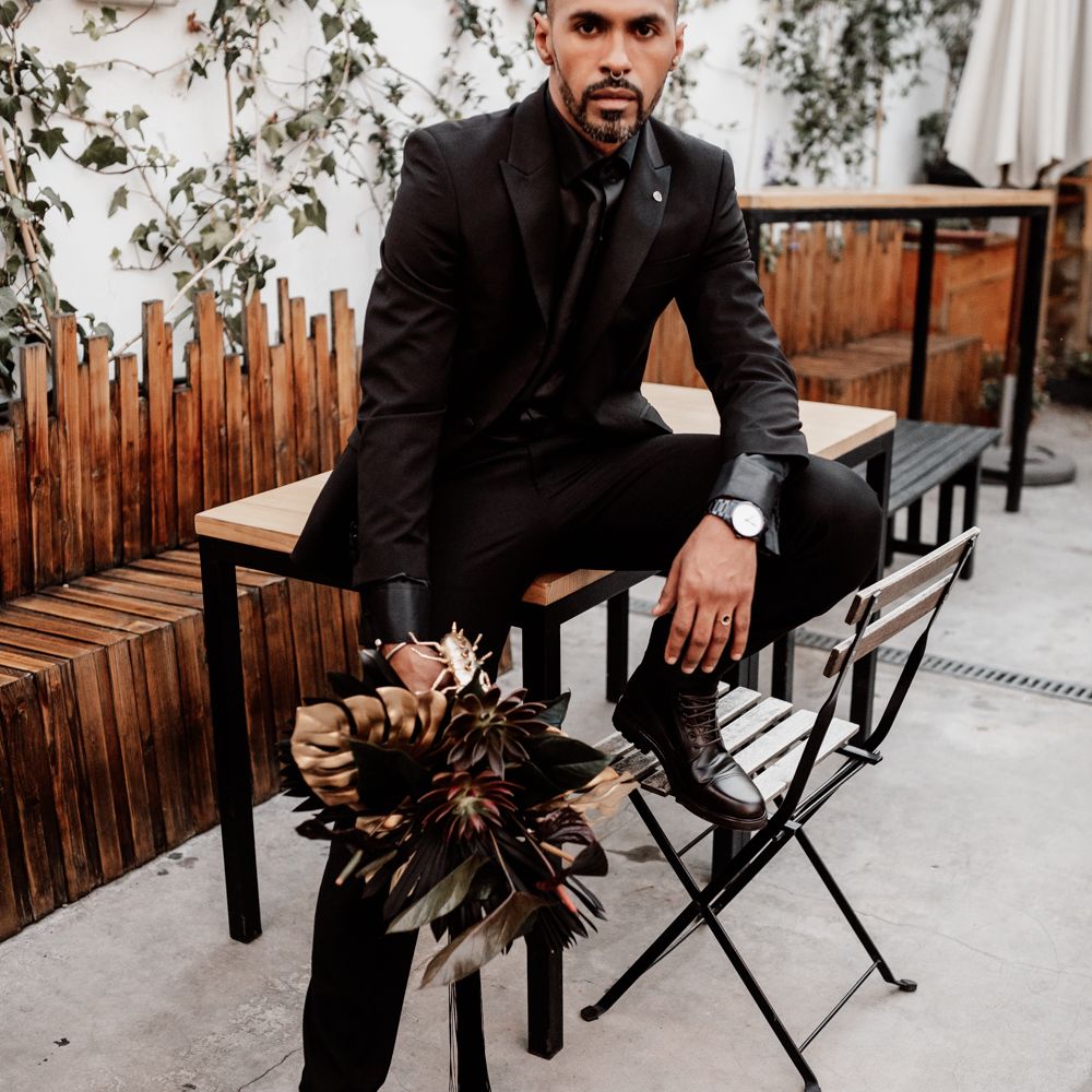 Groom in black suit holding bouquet 