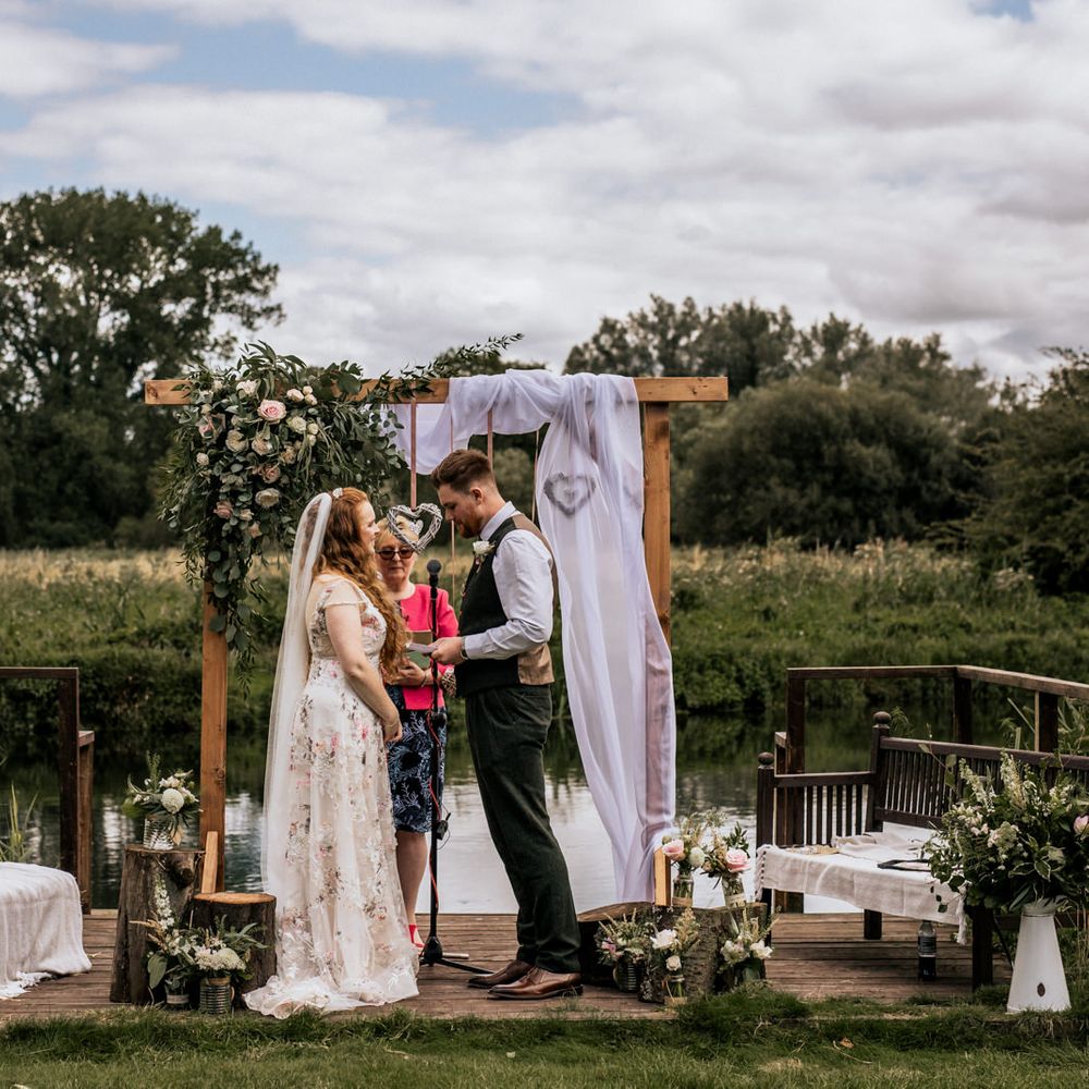 Bride and groom under wooden archway with floral decoration 