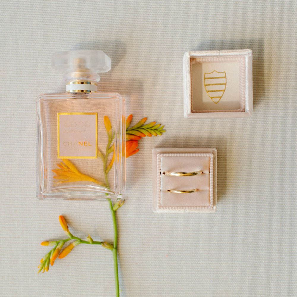 Two simple gold wedding bands with a bottle of Chanel perfume