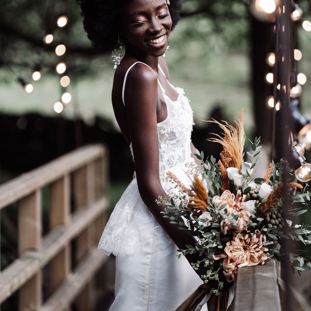 Smiling bride in a lace peplum wedding dress standing on a bride at Ponden Mill wedding venue 