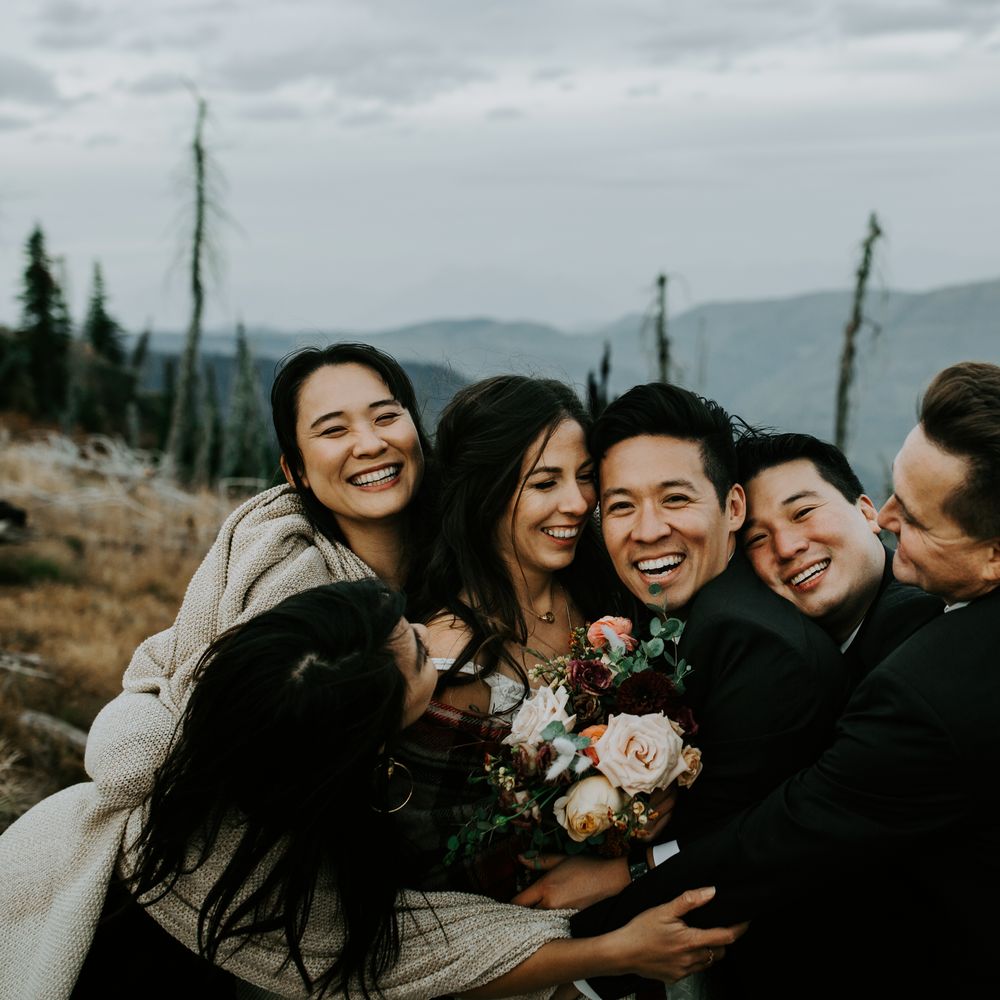 Bride & groom laugh and smile with wedding party