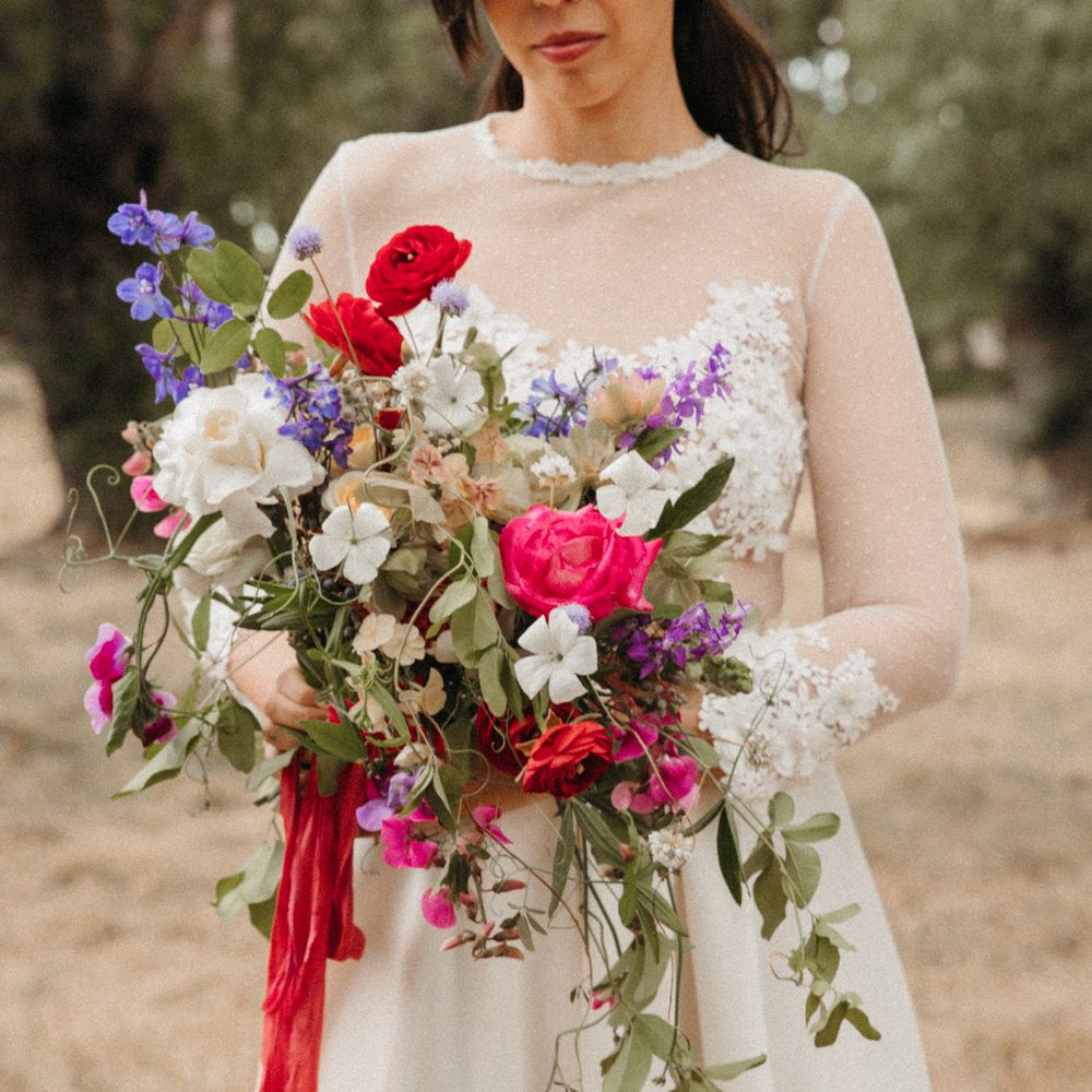 Bride holds colourful bouquet tied with pink ribbon