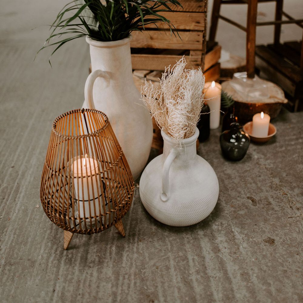 Tropical wedding decor with rattan candle holders, ceramic vases and tropical plants