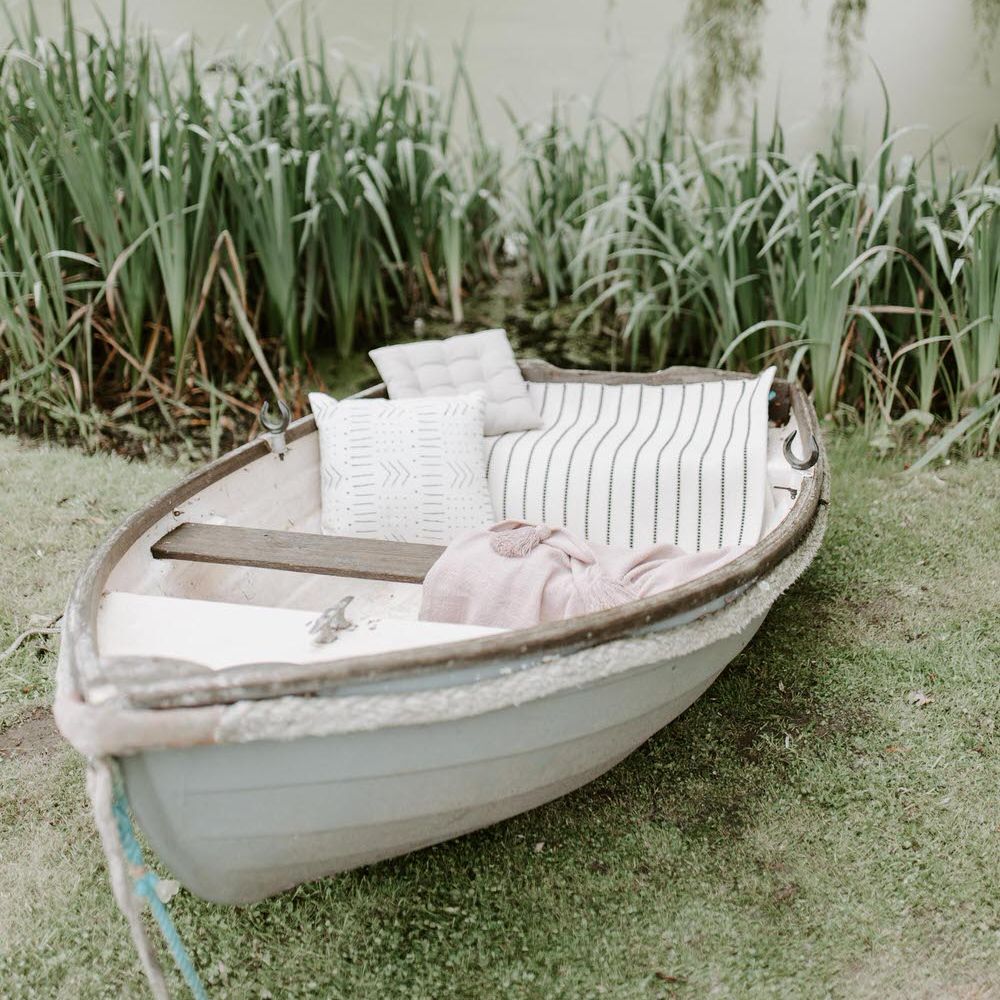 A white rowboat next to an algae covered lake