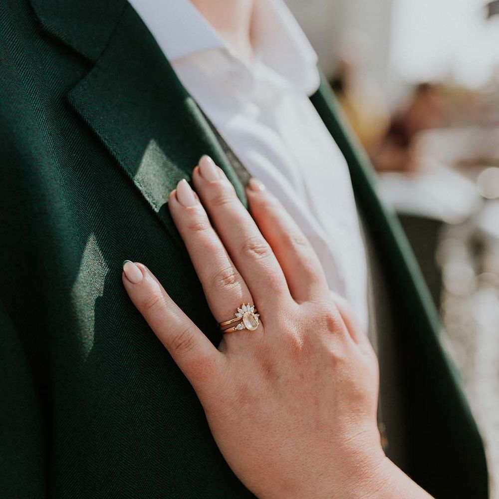 Bride places her hand on grooms jacket complete with vintage styled engagement ring and green tipped French wedding nails
