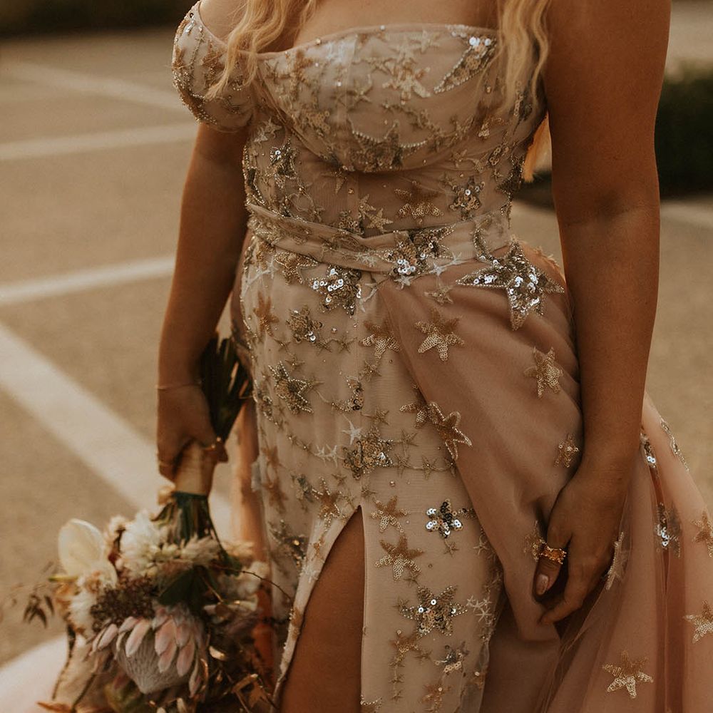 Bride walks with her floral bouquet in hand and holds detachable skirt to the side