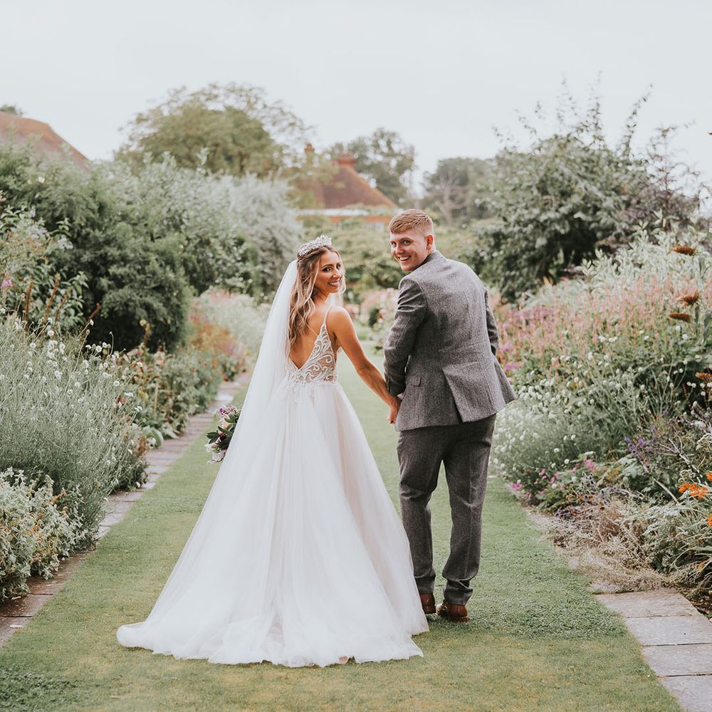 Bride and groom walk in the gardens at country house wedding venue