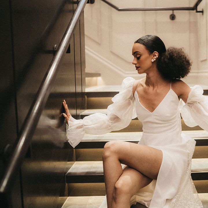 Black bride in a slip wedding dress with detachable long sleeves, shaped back hair and pearl earrings 