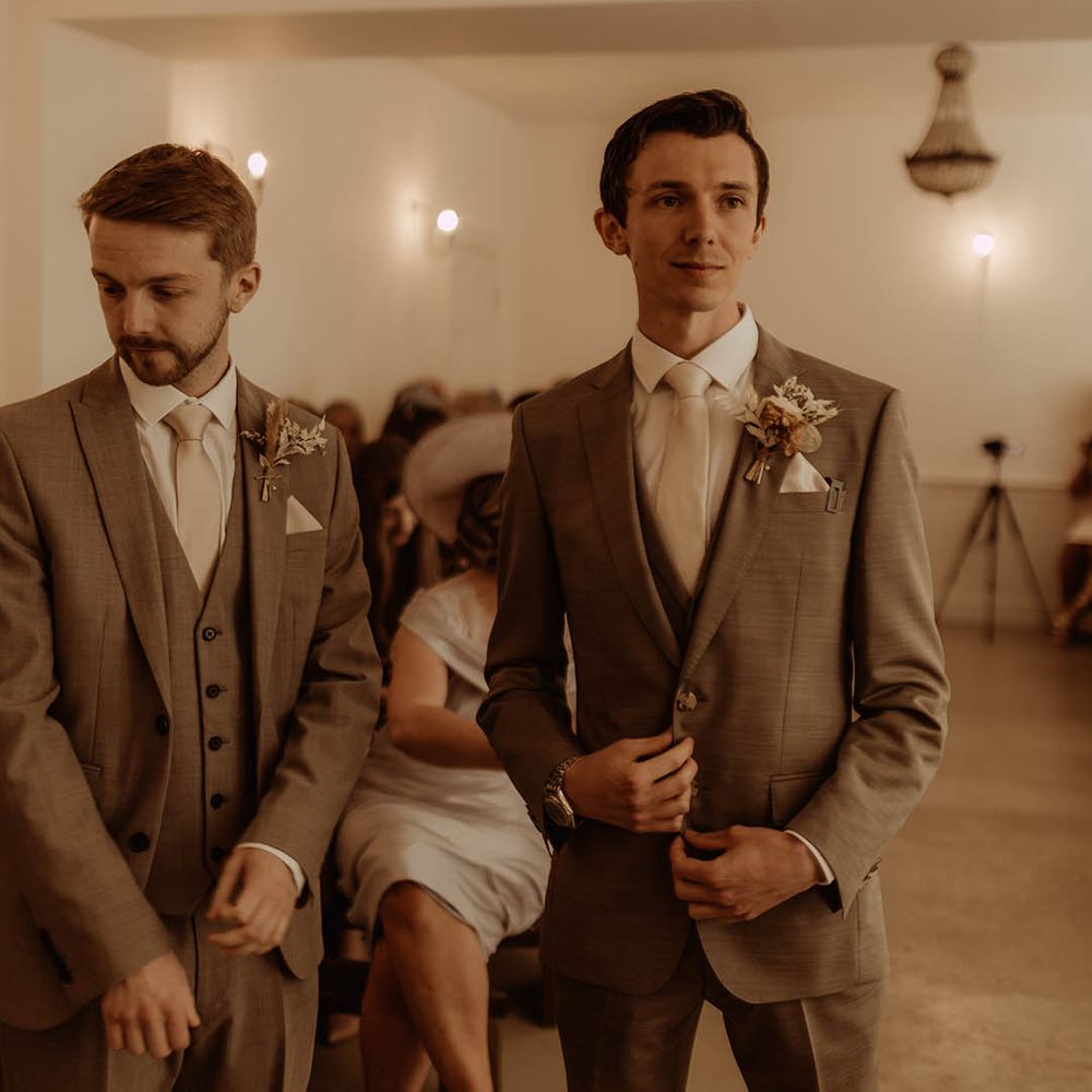 Groom in three piece neutral suit with the best man in matching outfit and dried flower buttonholes 