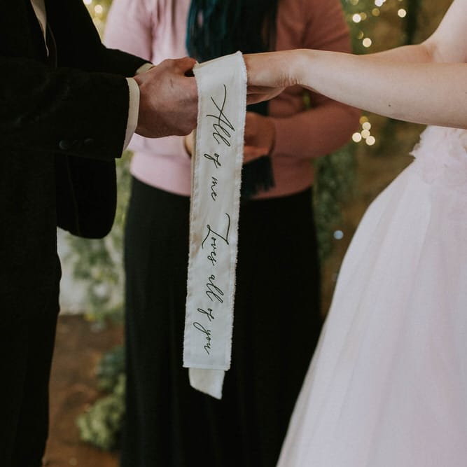 handfasting ceremony with 'all of me loves all of you' inscribed ribbon