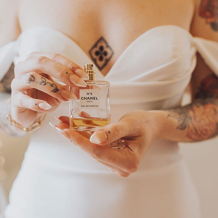 Bride holds Chanel No.5 perfume complete with french tip manicured nails