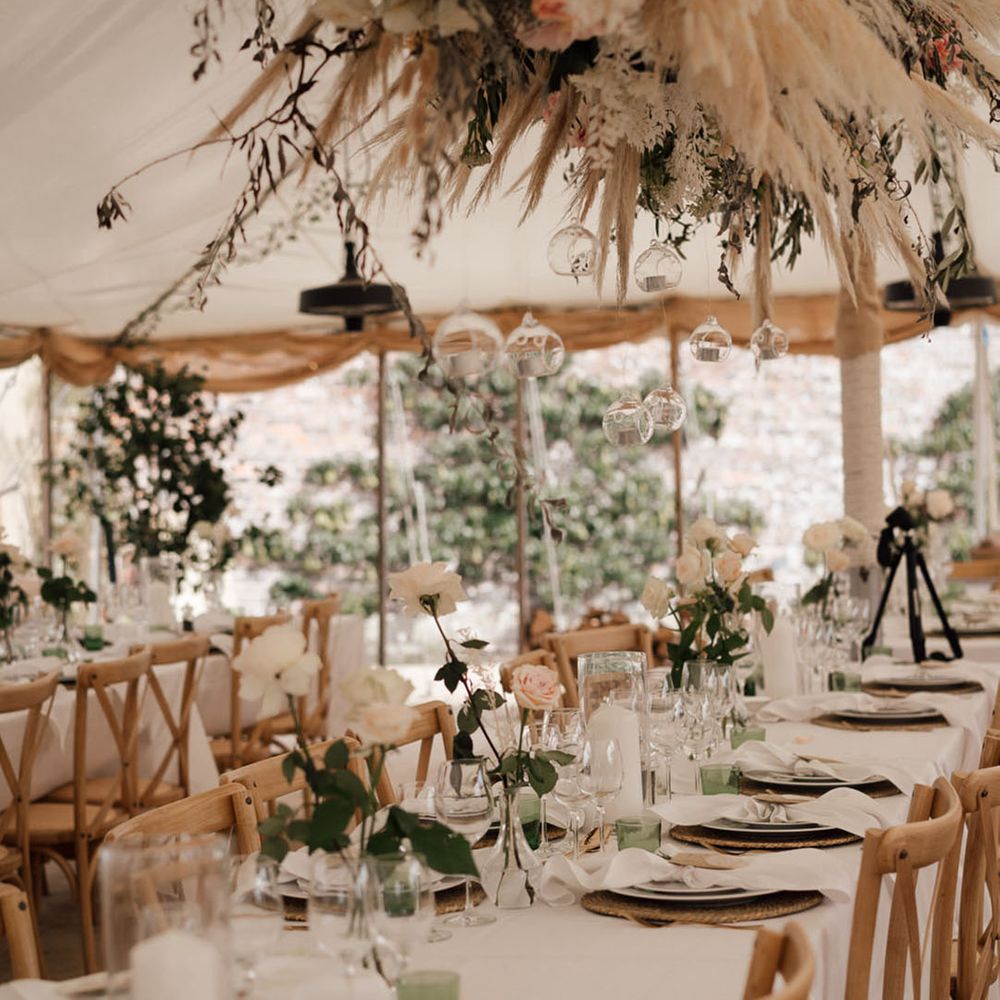Flower installation with pink roses and flowers with pampas grass over the tables with a green and white theme 
