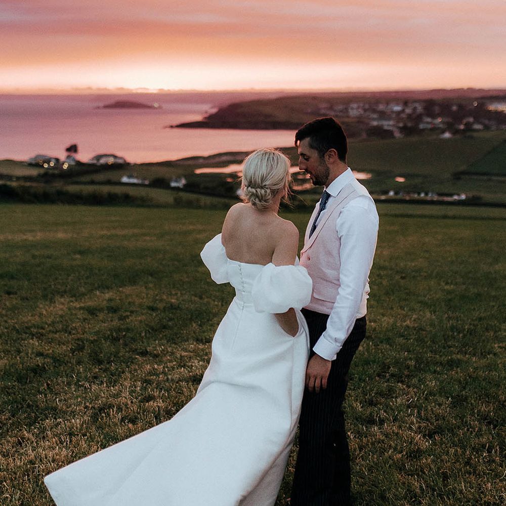 Bride & groom stand outdoors during beautiful sunset for Salcombe wedding beside the sea 