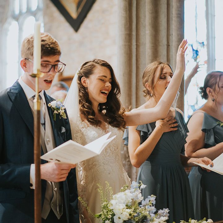 The bride and groom singing worship songs for the Christian wedding with the bridesmaids and rest of the wedding party 