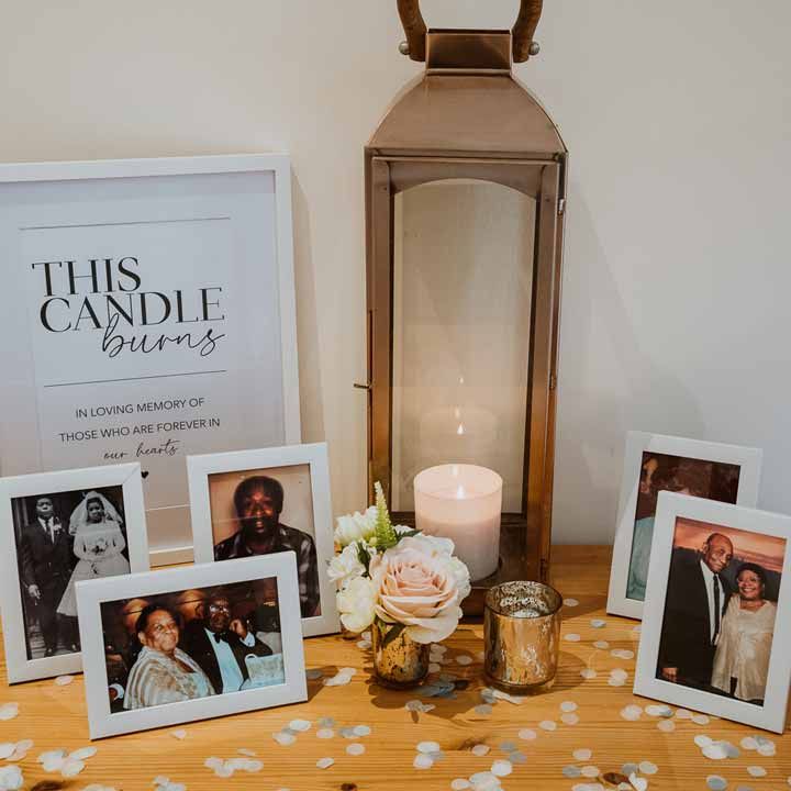 In loving memory table at Tredudwell Manor wedding with large candle, blush rose, white photo frames and photos of those in loving memory