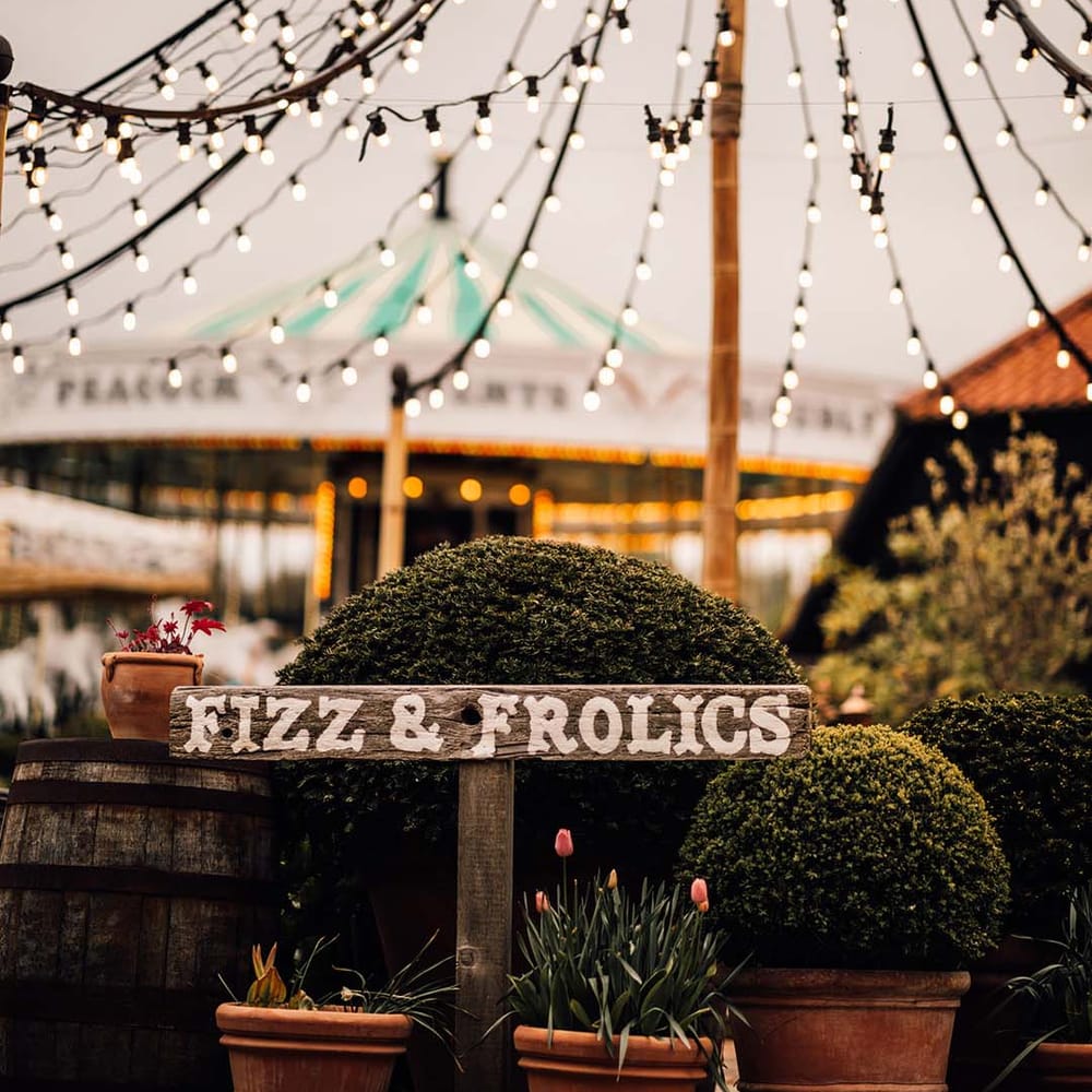 Wooden directional signage at the outdoor wedding venue with festoon lighting 