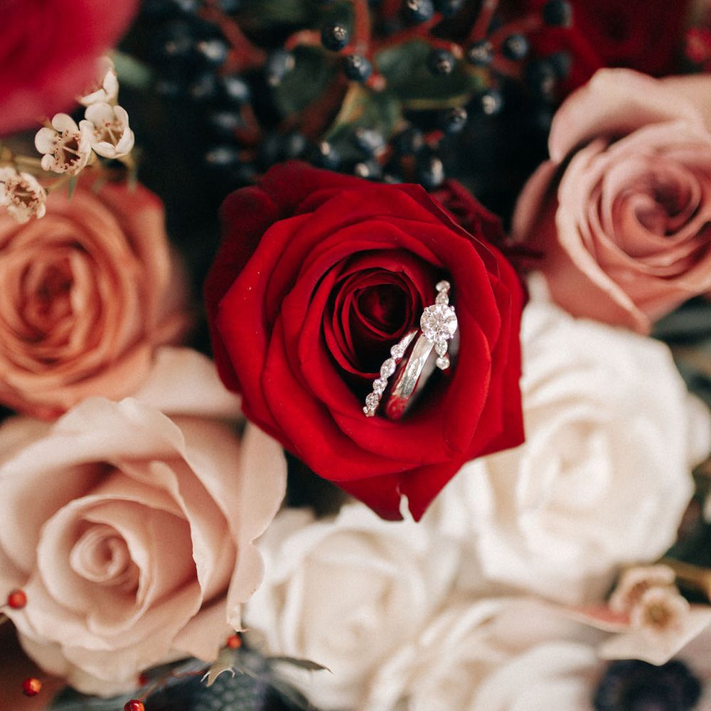 Red and white rose wedding bouquet with diamond engagement ring and wedding band for the bride 