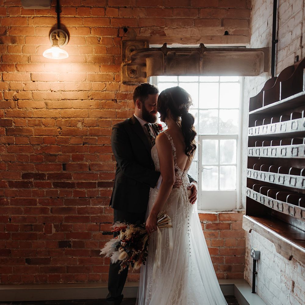 Romantic couple portrait with bride in lace wedding dress gazing at the groom 