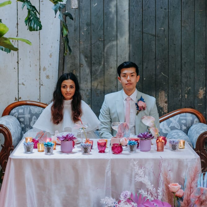 Bride and groom dining at their holographic pastel sweetheart table 