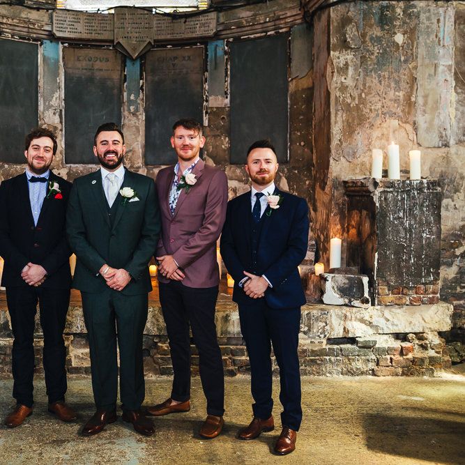 Groom stands with his groomsmen in different coloured suits