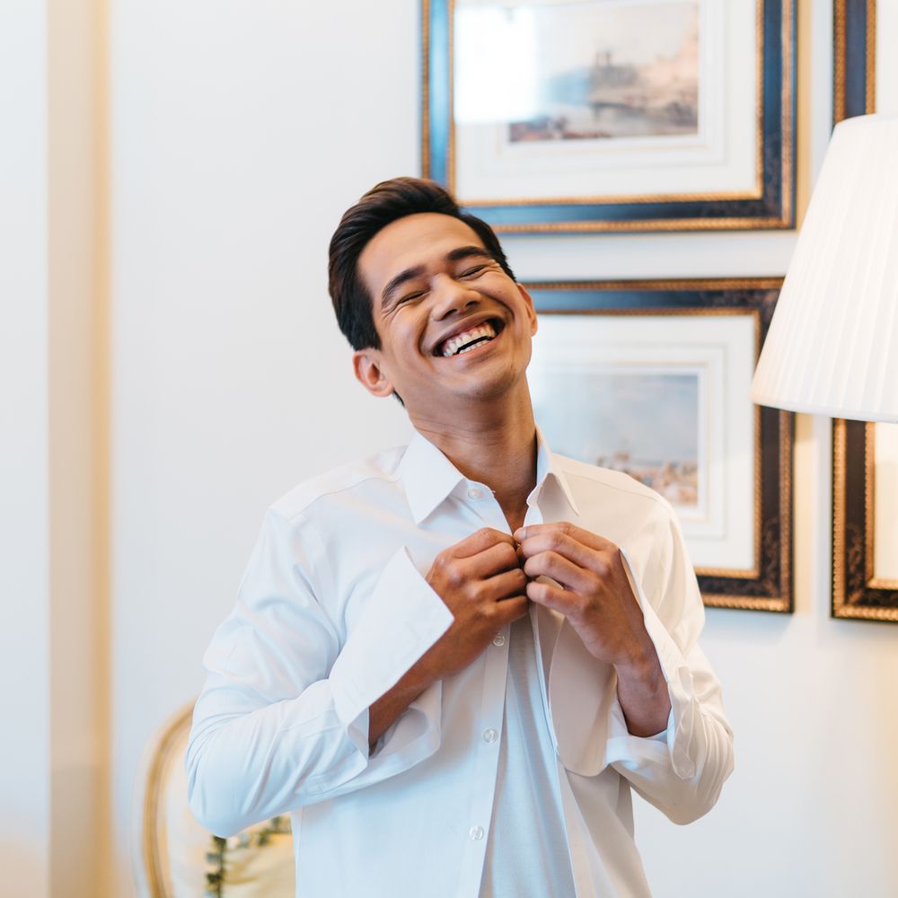 Groom laughs and gets ready on the morning of his wedding