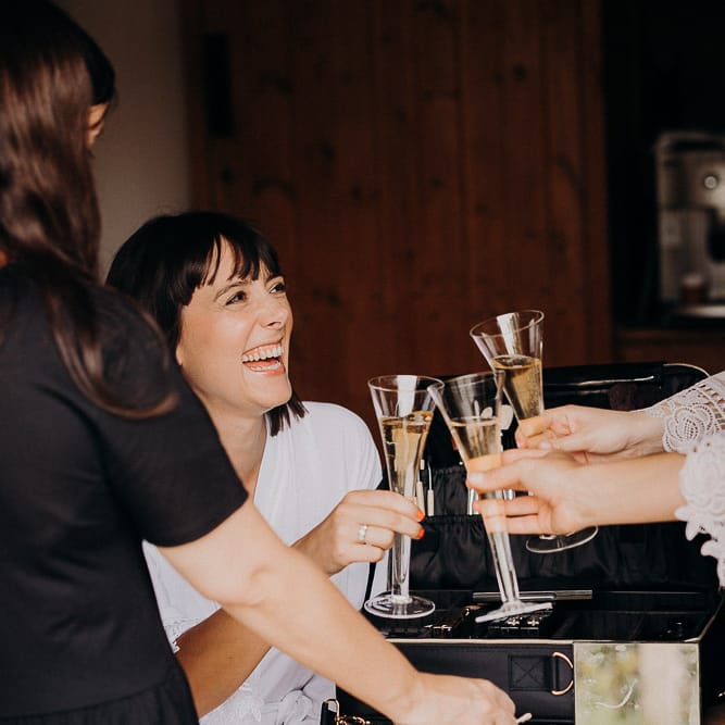 Bride and bridesmaids on the wedding morning sipping champagne 