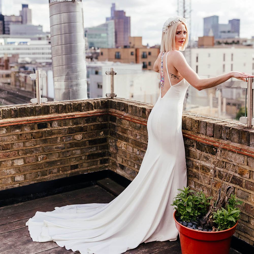 Bride in a low back wedding dress with then straps and jewel body art 