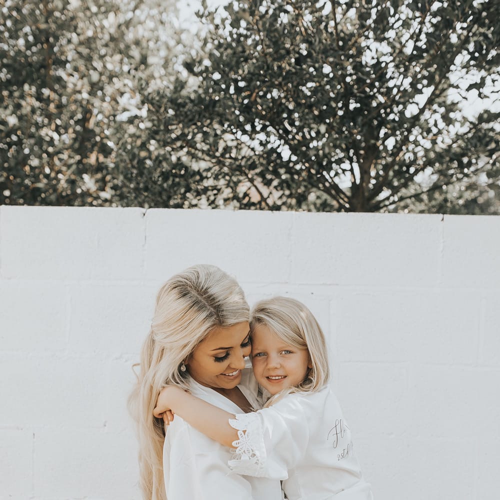 A bride cuddles her daughter as they get ready for her wedding. 