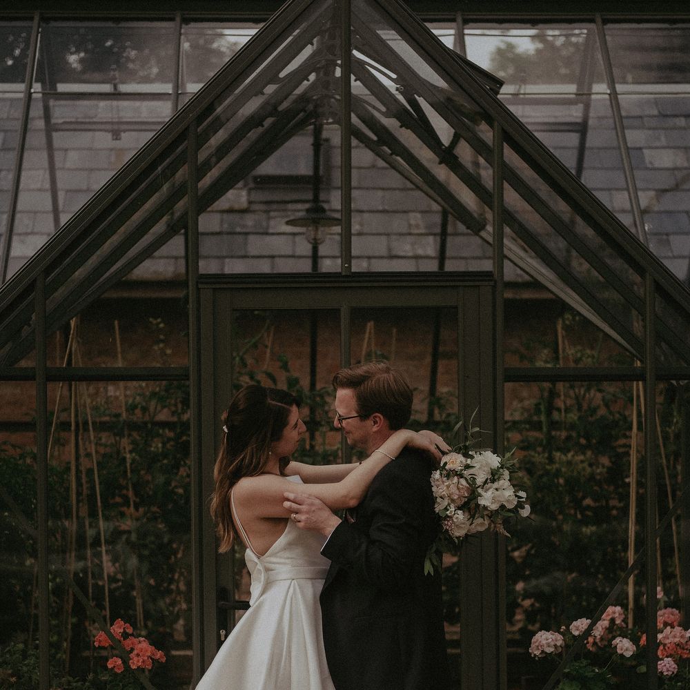 Bride & groom embrace outside greenhouse at Elmore Court on their wedding day