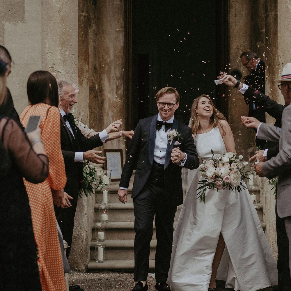 Bride & groom leave wedding ceremony as confetti is thrown around them