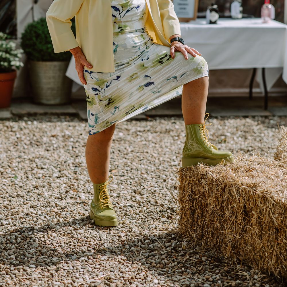 Wedding guest puts her leg up on hay bale for Park Farm wedding as the sun shines