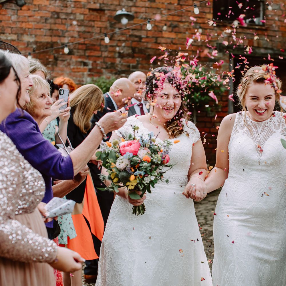 Brides walk through confetti with one another after wedding ceremony for Park Farm wedding