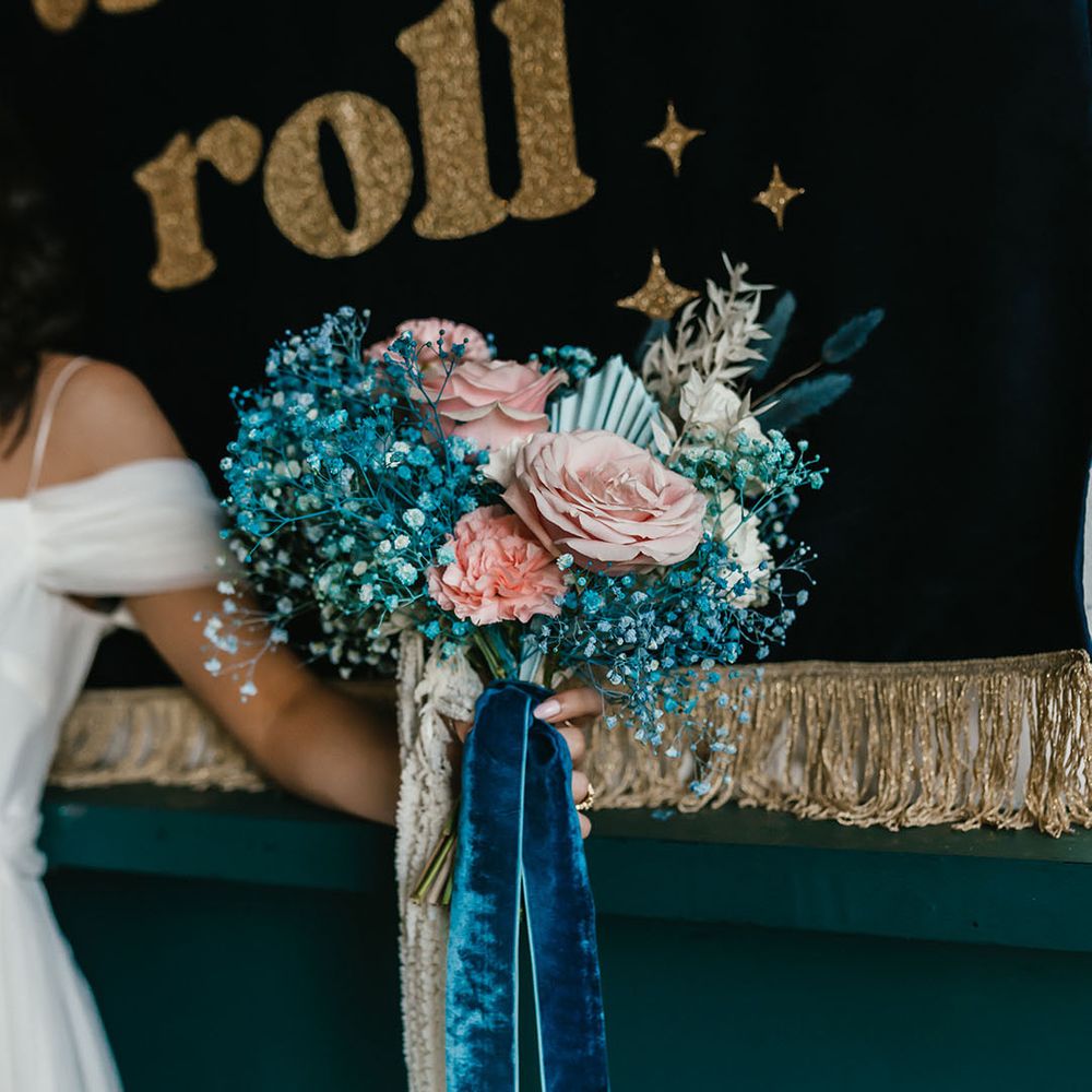 Pink roses and carnations and teal gypsophila wedding bouquet tied with ribbon 