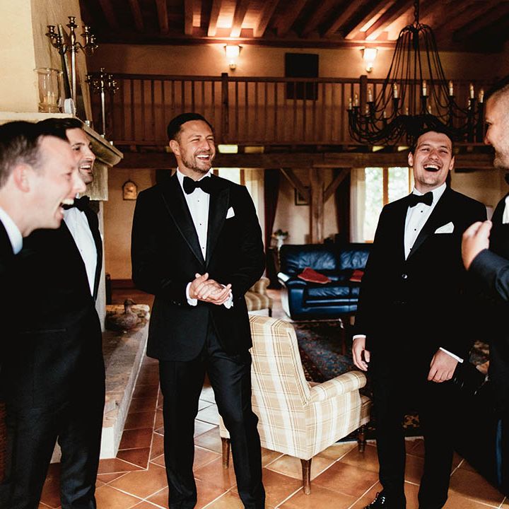 Groom laughs with his groomsmen as they wear black tie on the morning of wedding day