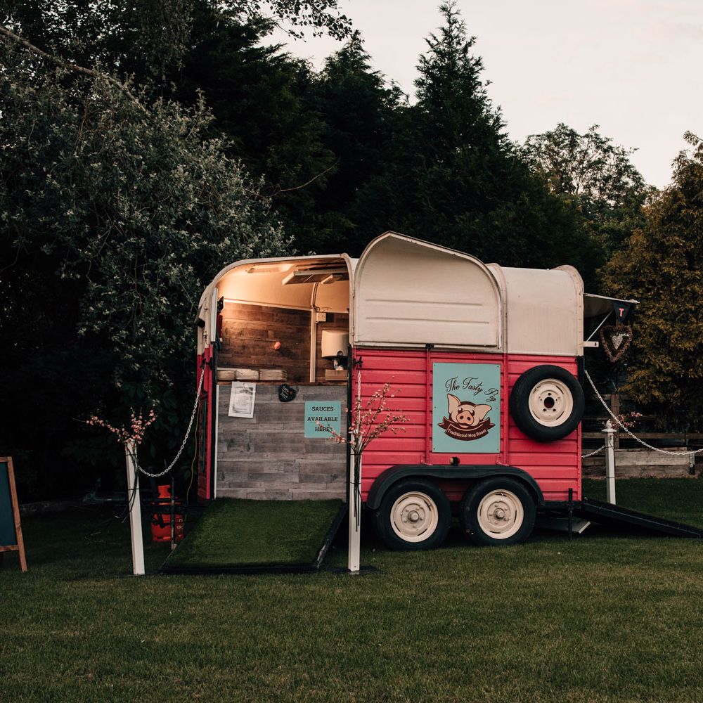 Hog roast trailer in field at outdoor wedding reception