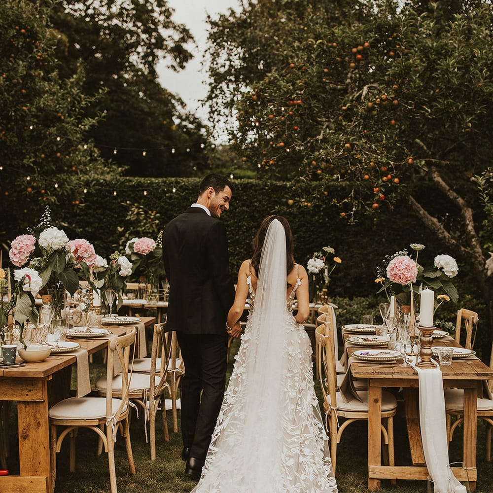 Bride & groom walk through reception garden with one another
