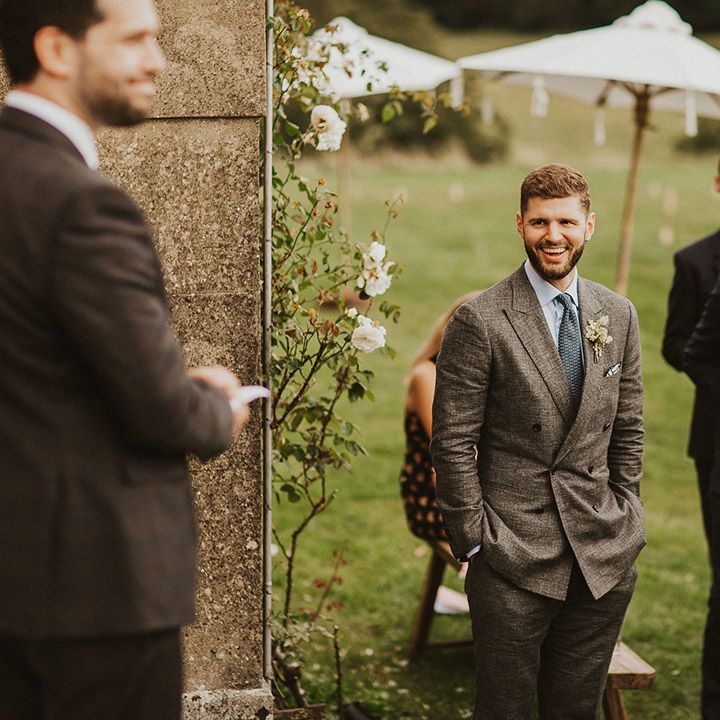 Groom smiles and laughs with friends on his wedding day