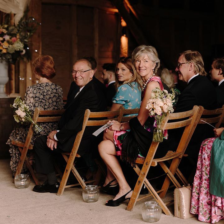 Wedding guests watch bride walk down the aisle at barn ceremony