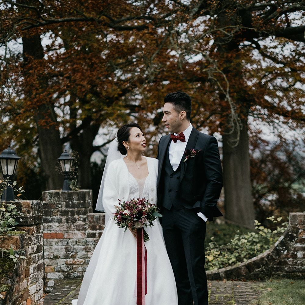Bride in cardigan cover up gazes at groom in tuxedo