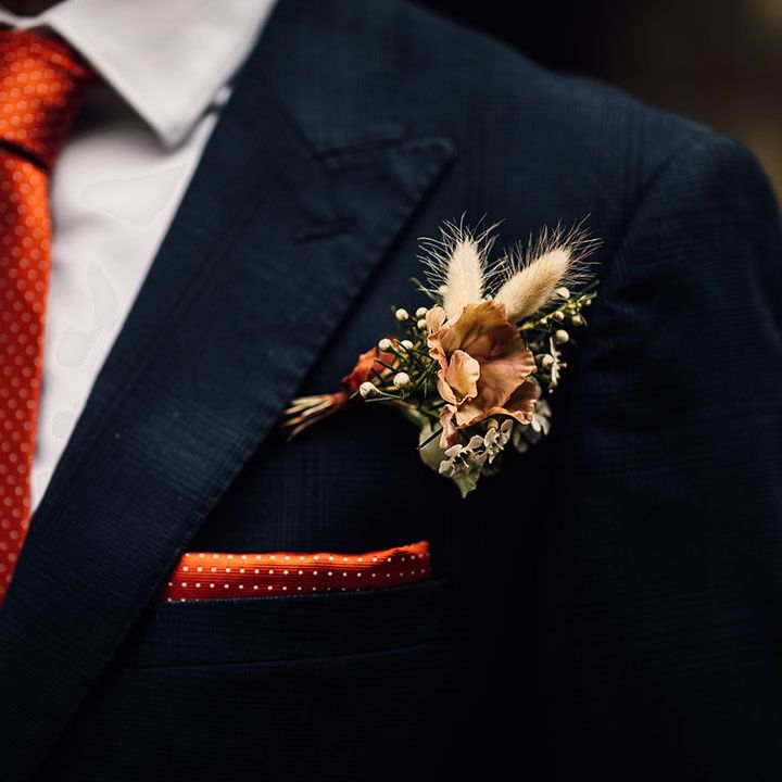 Grooms polka dot orange and white tie and pocket square with dried flower and bunny ears button hole 