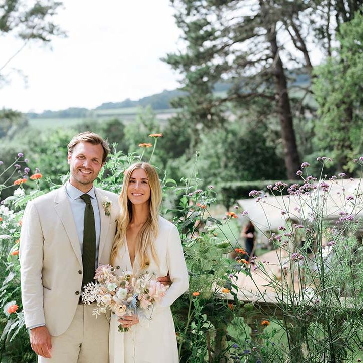 Bride in bespoke Bon Bride wedding dress with groom in cream suit pose together with views of their garden