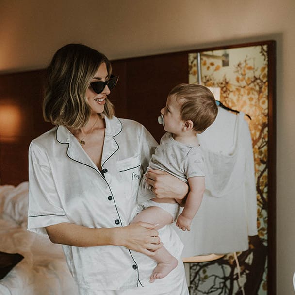 Bridal preparations for the wedding day with bride in satin pyjamas holding baby 