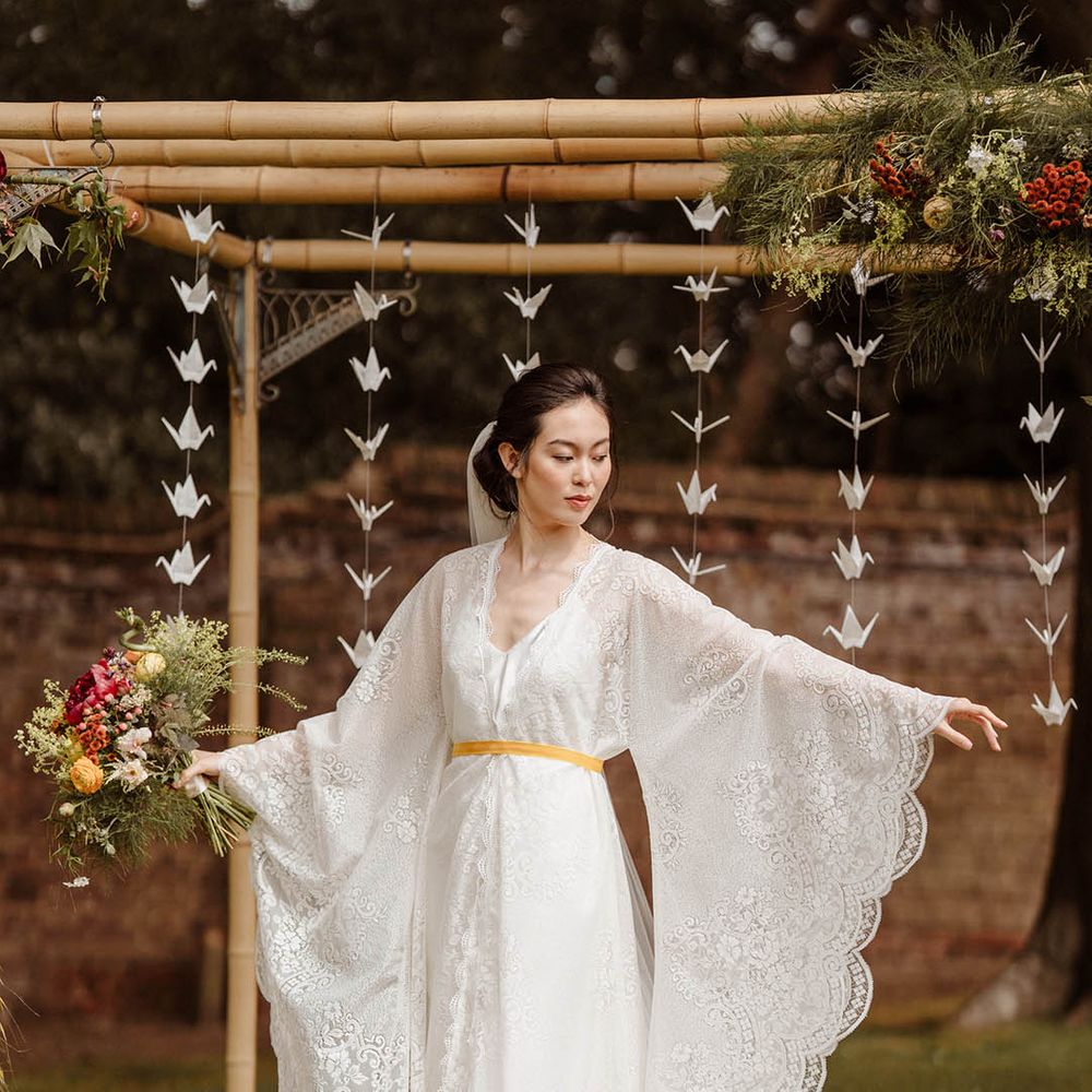 East Asian bride in a lace Kimono style wedding dress with long sleeves tied with yellow ribbon at Japanese wedding at Gorse Hill