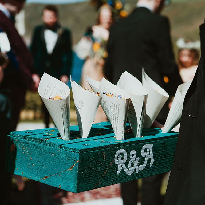 Colourful confetti in white paper cones stood in blue wooden box painted with R&A