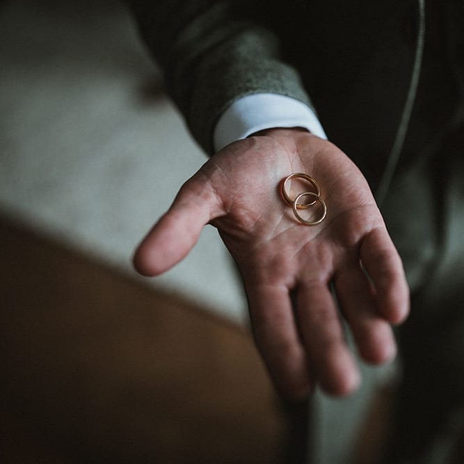 Groom holds gold wedding bands on the morning of his wedding day