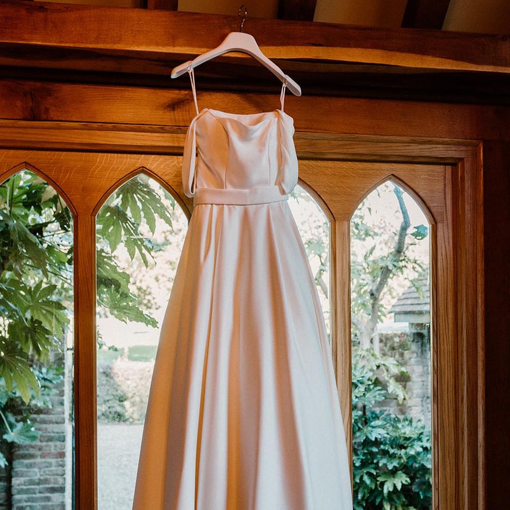 The bride's wedding dress from Love and Loved Bridal hangs up 