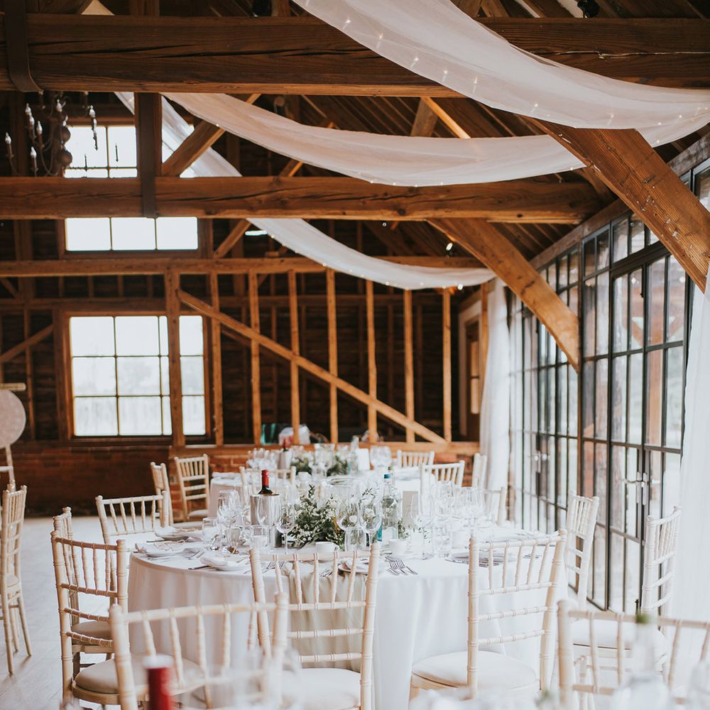 Classic and traditional wedding table setting with white wedding flowers and white drapes