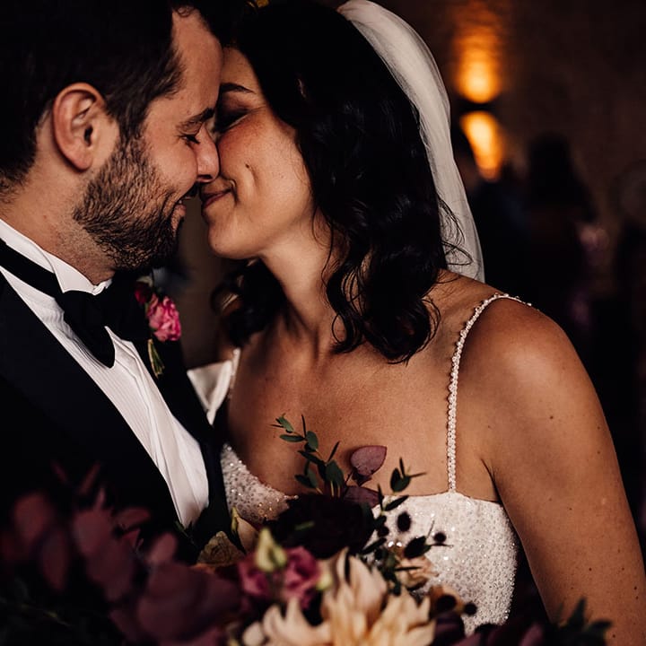 The bride and groom share an intimate moment as they lean in for a kiss 