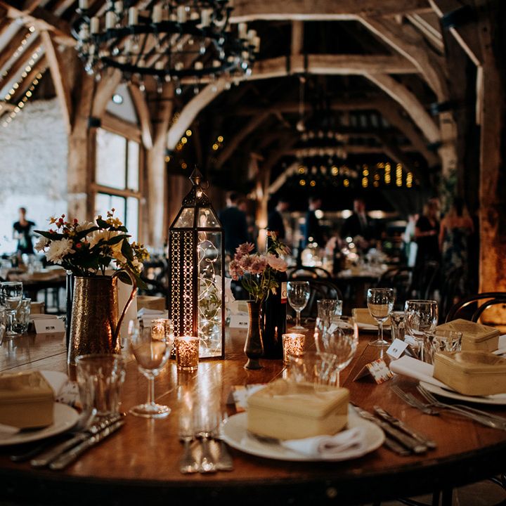 Rustic tablescape complete with fairy lights in lantern and small floral arrangements 