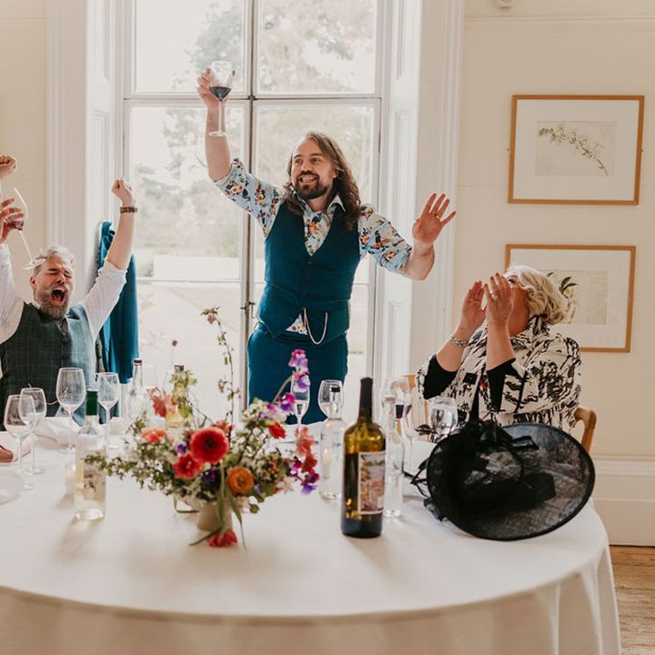 Grooms laugh during wedding speeches for wedding in Kew Gardens
